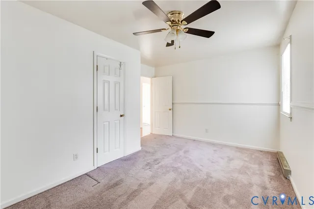 an empty room with chandelier fan and windows