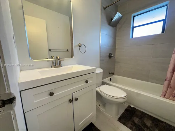 a bathroom with a bathtub shower sink vanity mirror and toilet