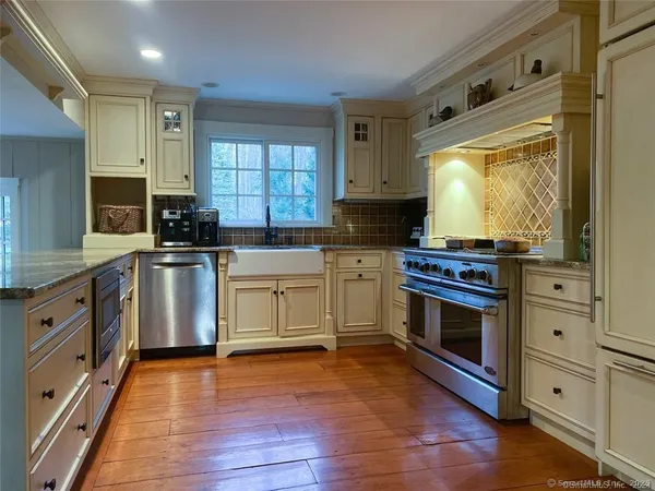 a kitchen with stainless steel appliances a white stove top oven cabinets and a wooden floor
