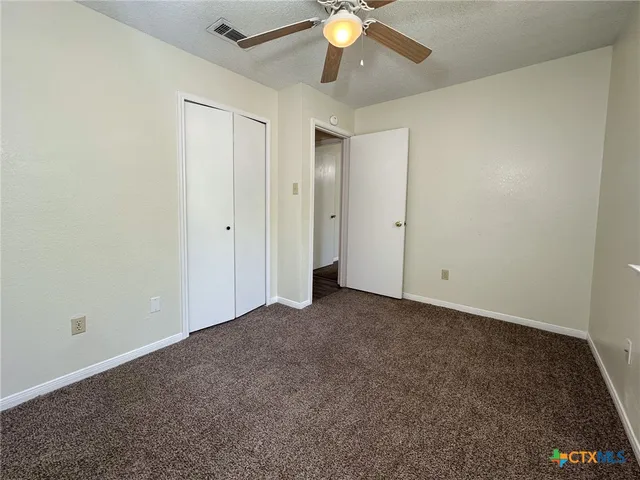 an empty room with a ceiling fan and a window
