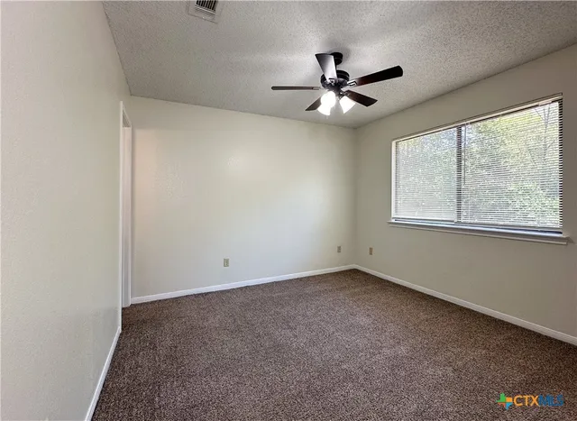 an empty room with windows and fan