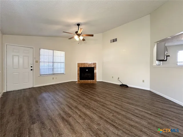 an empty room with wooden floor chandelier fan and windows