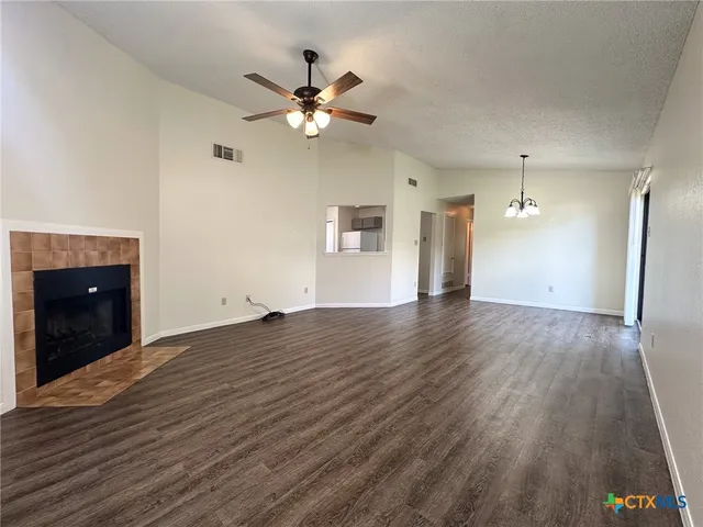a view of an empty room with wooden floor and fan