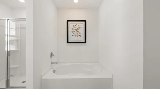 a white bath tub sitting next to a white wall