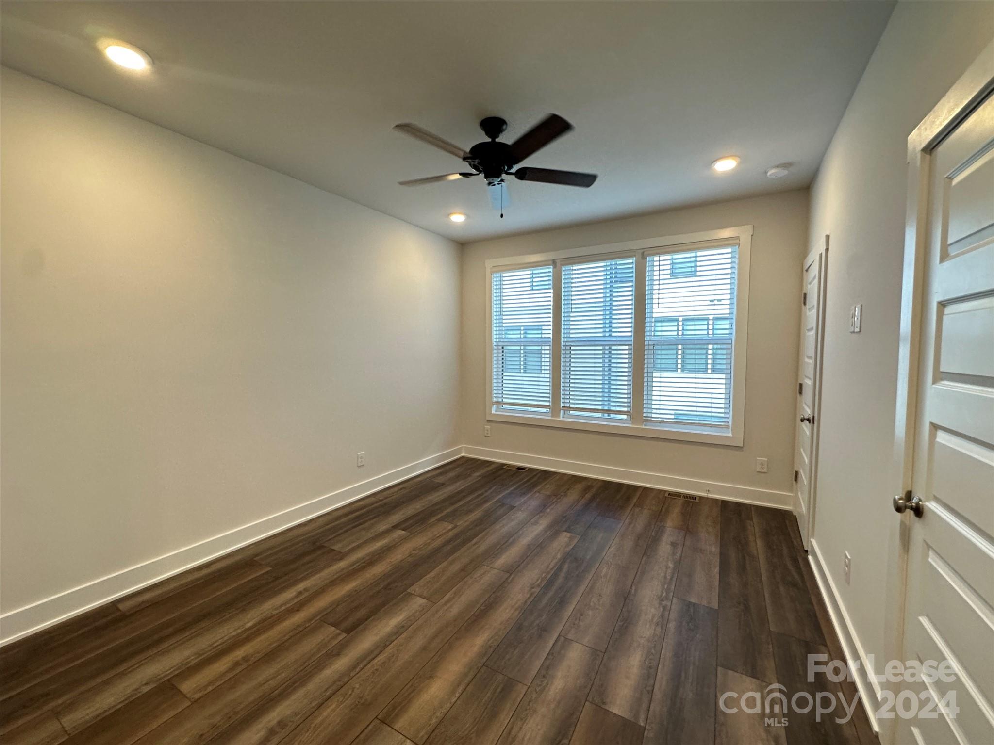 2124 Terwilliger Trail Charlotte, NC 28203 - Photo 15 of 36 an empty room with wooden floor a ceiling fan and windows