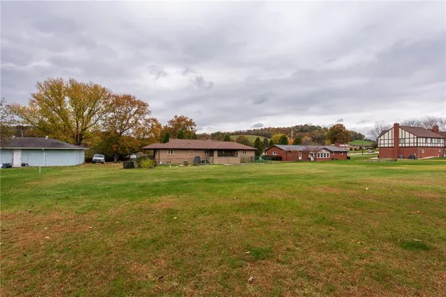 a front view of house with yard and trees in the background