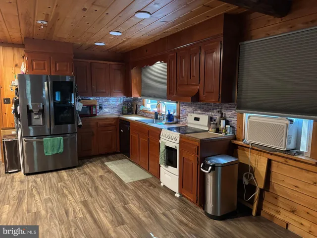 a kitchen with stainless steel appliances granite countertop a stove a sink dishwasher and a refrigerator with wooden floor