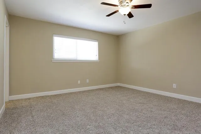 an empty room with a window and a fan