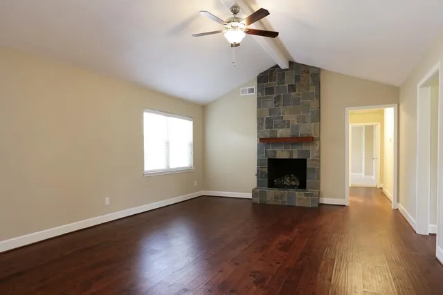 a view of an empty room with wooden floor fireplace and a window