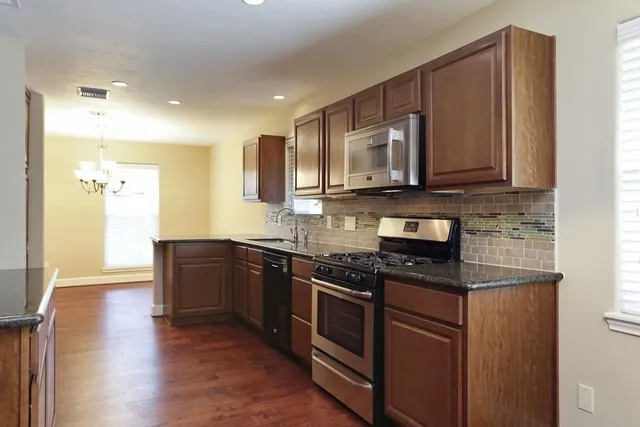 a kitchen with stainless steel appliances granite countertop wooden cabinets and a stove top oven