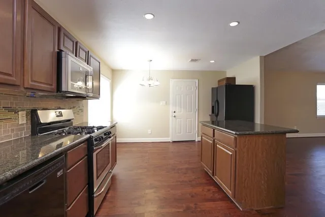 a kitchen with stainless steel appliances granite countertop a stove a sink and a refrigerator