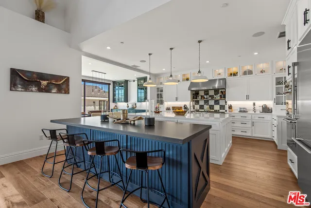 a kitchen with stainless steel appliances granite countertop a table chairs sink and cabinets