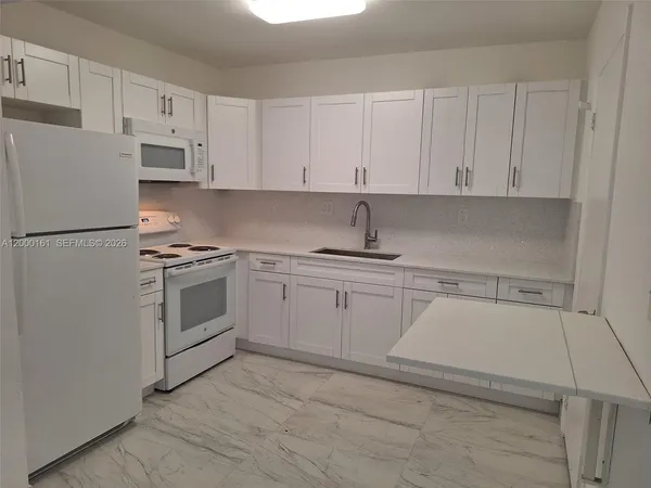 a kitchen with white cabinets and white appliances