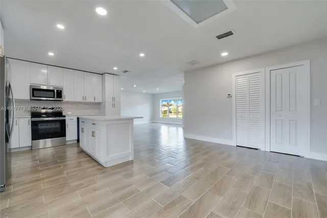a view of kitchen with kitchen island granite countertop stainless steel appliances refrigerator sink and cabinets