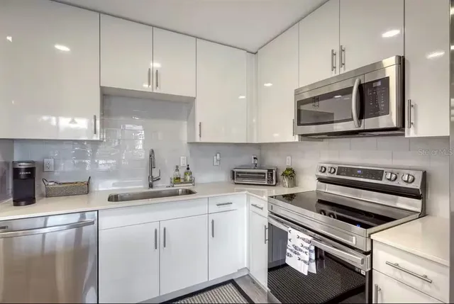 a kitchen with stainless steel appliances granite countertop a sink a stove a microwave and wooden cabinets