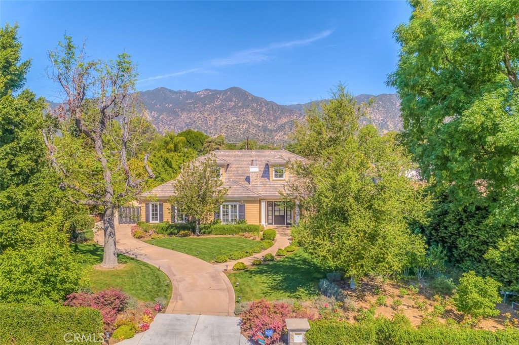 a front view of a house with a yard and a large tree