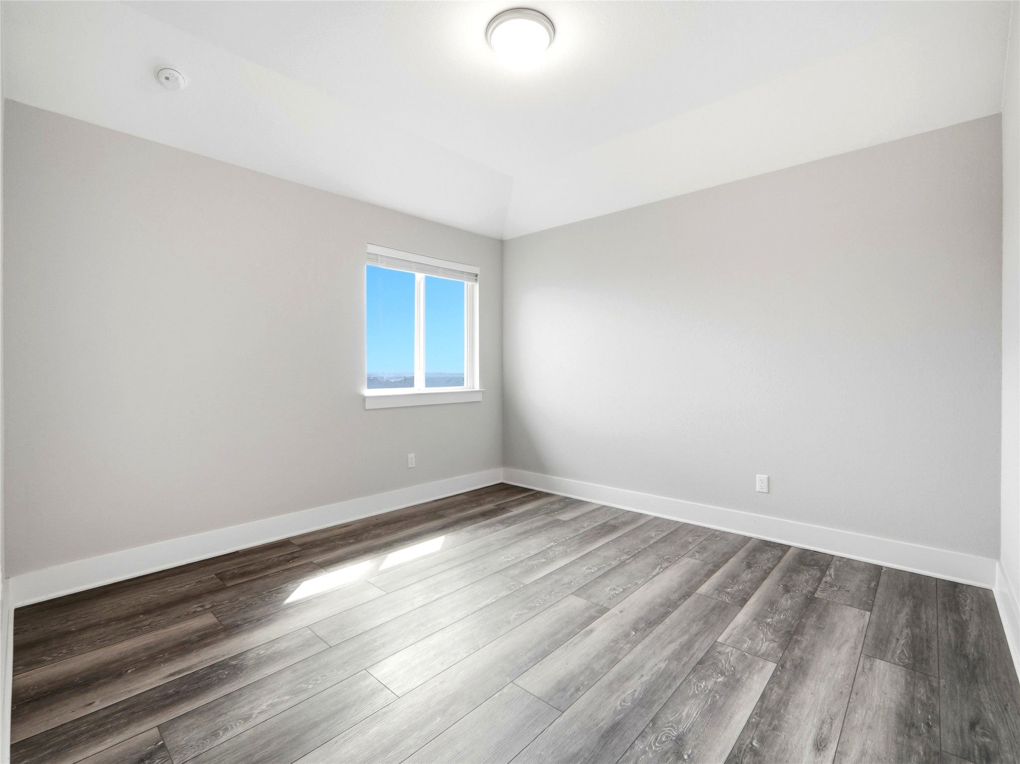 848 Wild Pecan Loop Buda, TX 78610 - Photo 11 of 49 Bright and airy bedroom with sleek flooring and ample natural light from a large window, perfect for relaxation and comfort.