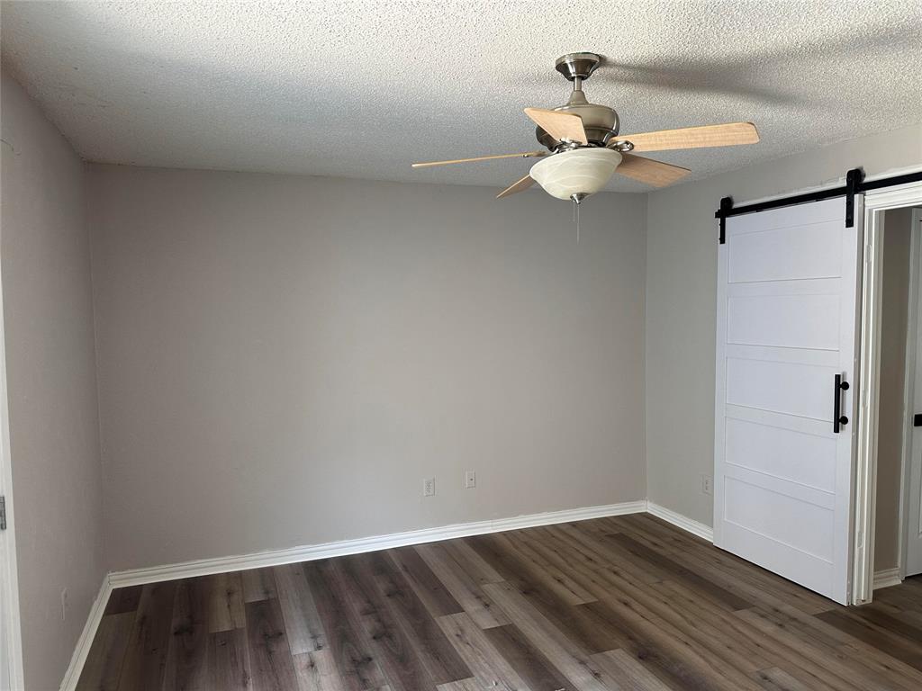 5324 Timber Creek Road Flower Mound, TX 75028 - Photo 10 of 14 featuring a barn door, ceiling fan, and dark hardwood / wood-style LVP floors