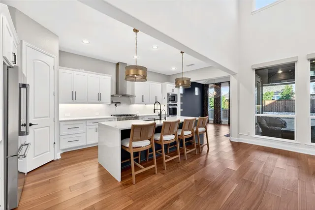 a kitchen with stainless steel appliances a sink dishwasher a stove and a refrigerator with wooden floor