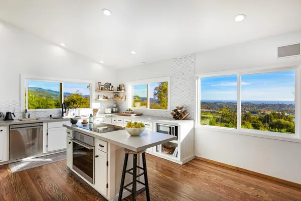 a view of a kitchen with kitchen island a large window a sink and counter top space