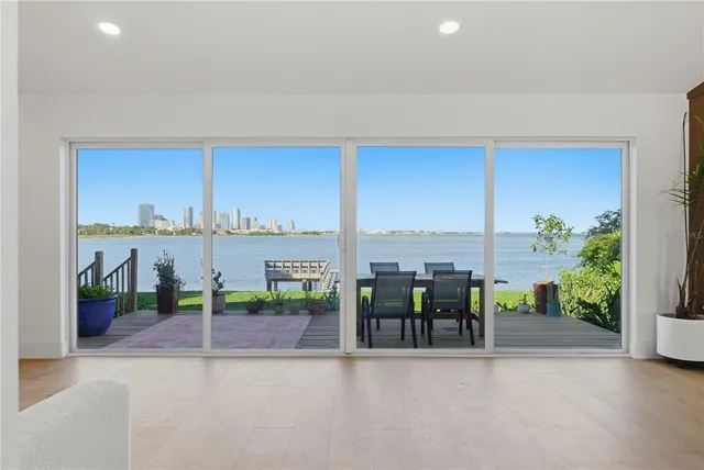 a kitchen with stainless steel appliances kitchen island granite countertop a refrigerator a stove a sink a dining table and chairs with wooden floor