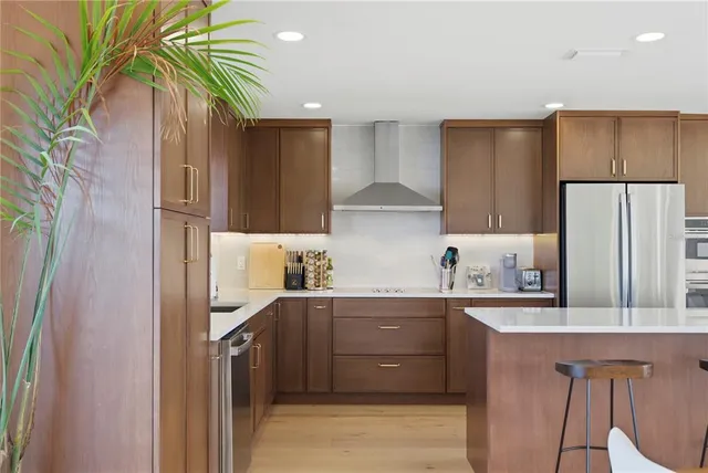 a kitchen with stainless steel appliances a refrigerator a sink a stove a dining table and chairs