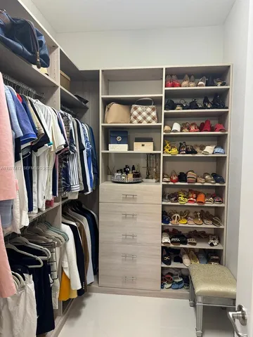 a view of walk in closet with clothes and shoes