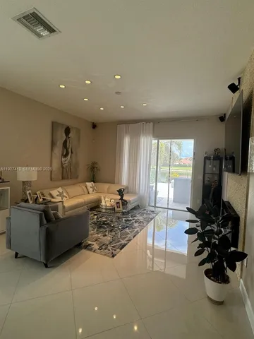 a living room with furniture a floor to ceiling window and a flat screen tv