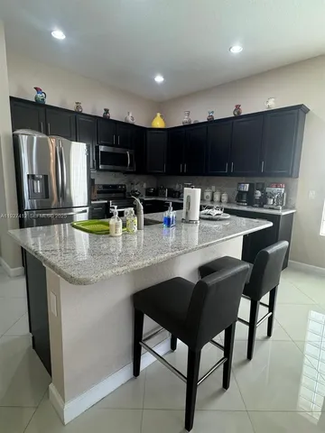 a kitchen with stainless steel appliances granite countertop a table chairs sink refrigerator and microwave