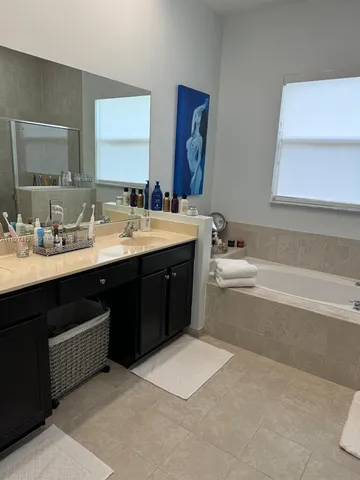 a spacious bathroom with a tub double sink and mirror