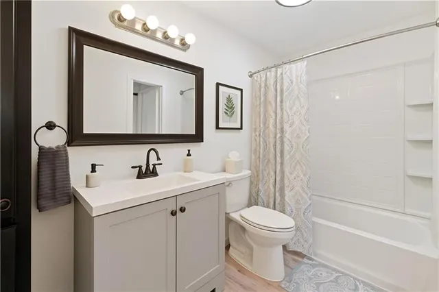 a bathroom with a white sink a toilet a mirror and shower