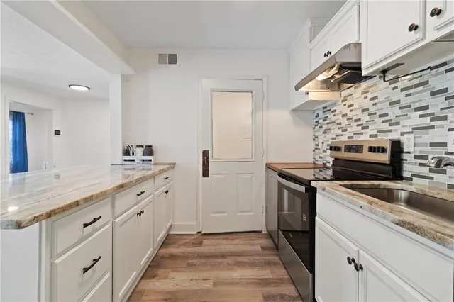 a kitchen with granite countertop cabinets stainless steel appliances and wooden floor