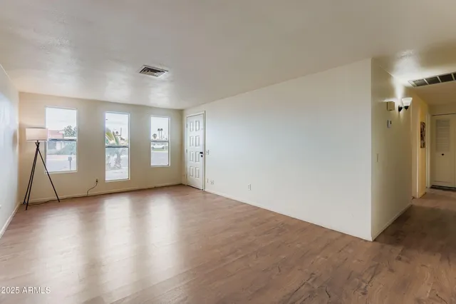 a view of an empty room with window and wooden floor