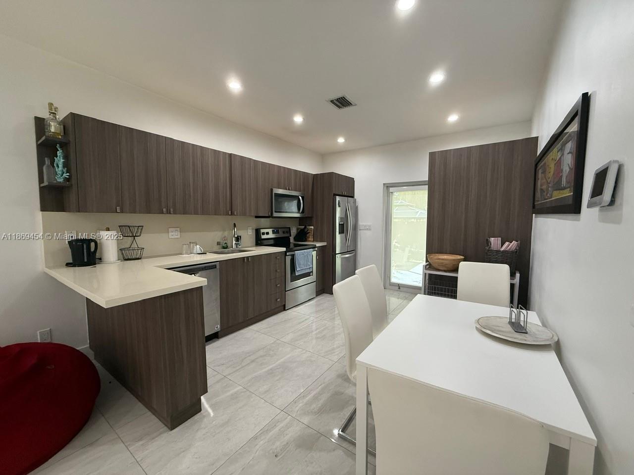 247 Northwest 58th Street Miami, FL 33127 - Photo 11 of 23 a kitchen with a sink a counter top space stainless steel appliances and cabinets