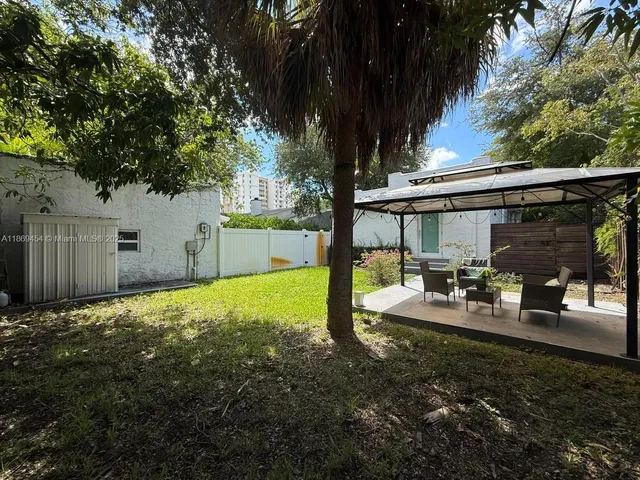 a view of a backyard with large tree and wooden fence