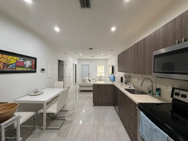 a large kitchen with lots of counter space a sink dishwasher a dining table and chairs with wooden floor