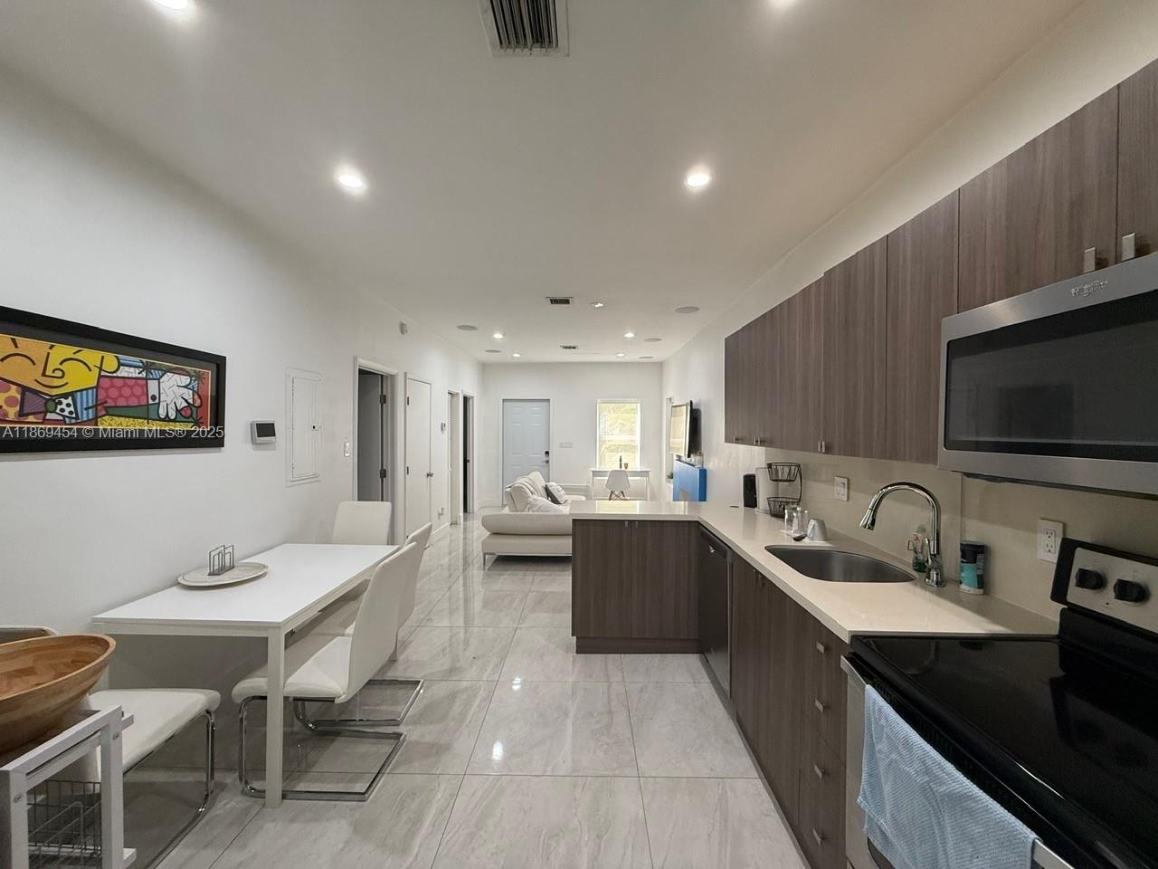 247 Northwest 58th Street Miami, FL 33127 - Photo 10 of 23 a large kitchen with lots of counter space a sink dishwasher a dining table and chairs with wooden floor