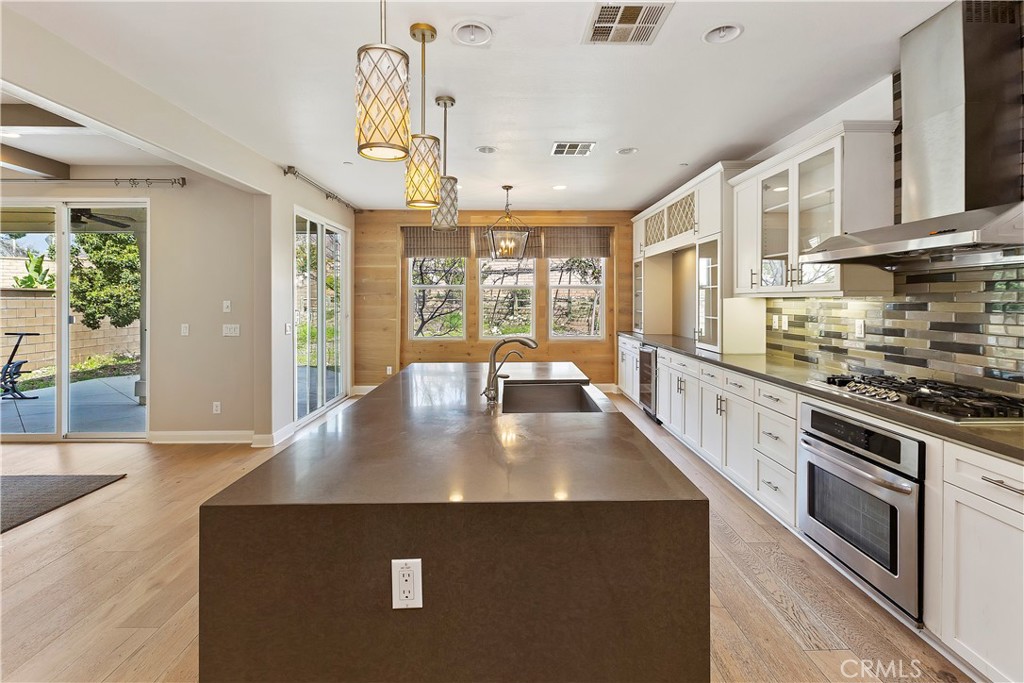 11548 Grimaldi Road Rancho Cucamonga, CA 91701 - Photo 19 of 39 a open kitchen with stainless steel appliances granite countertop a stove top oven a sink dishwasher a dining table and chairs with wooden floor