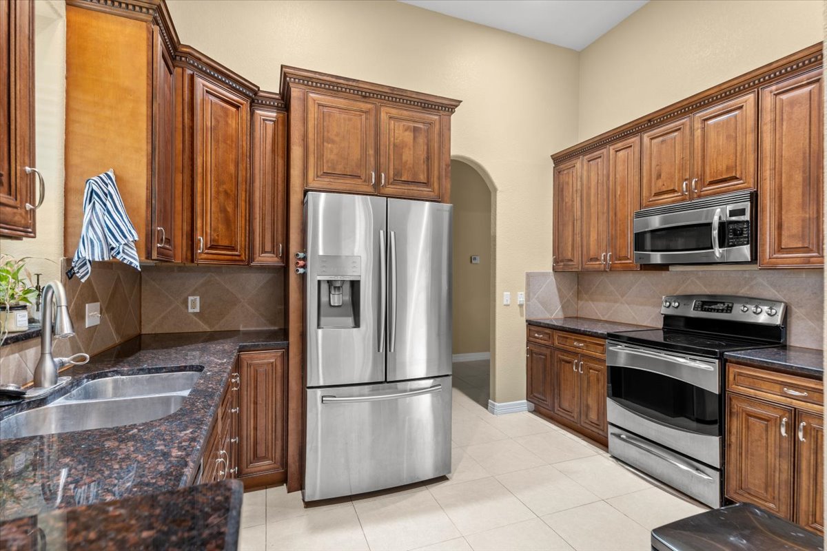 437 Balch Road Elgin, TX 78621 - Photo 8 of 37 Culinary aspirations come alive in this kitchen, featuring rich cabinetry and modern appliances.