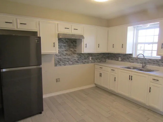 a kitchen with granite countertop white cabinets and refrigerator