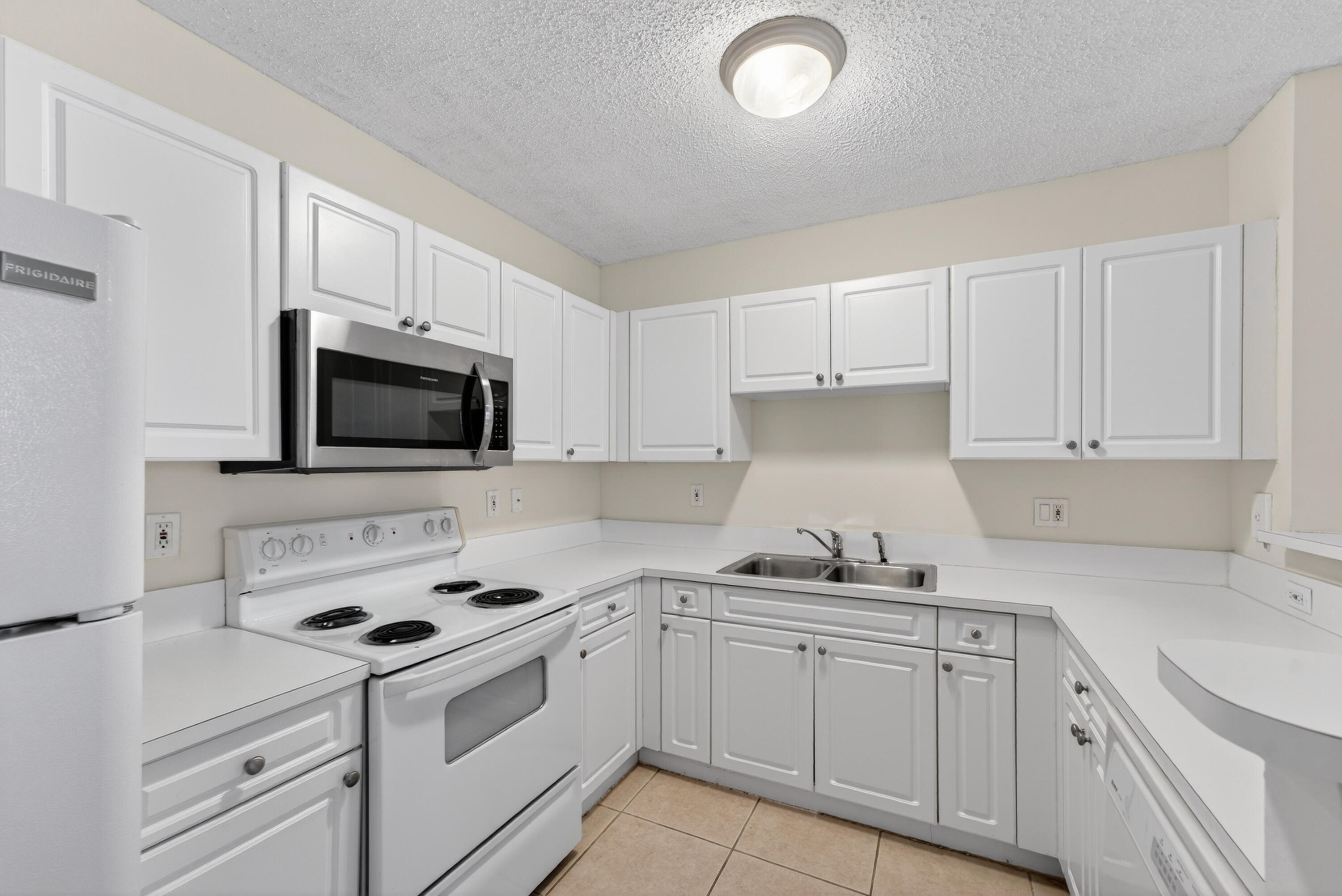 651 Okeechobee Boulevard, Unit 302 West Palm Beach, FL 33401 - Photo 5 of 29 a kitchen with white cabinets and white appliances