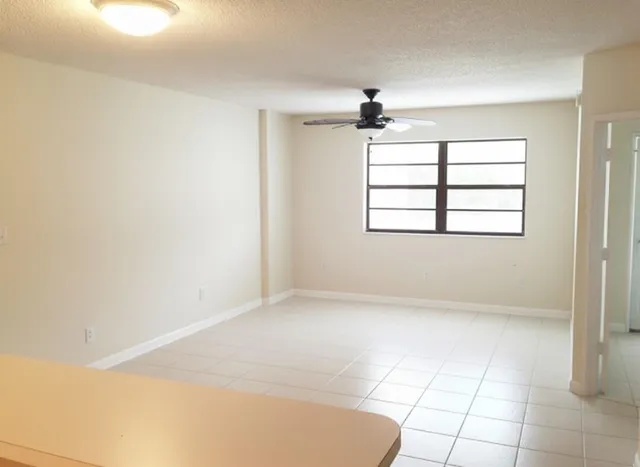 an empty room with windows and fan