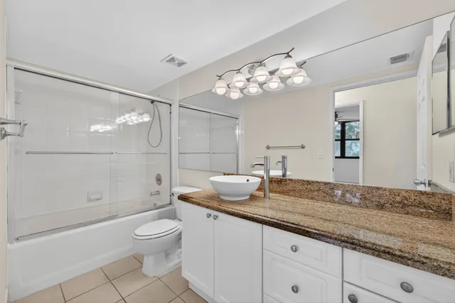 a bathroom with a granite countertop sink a toilet and shower