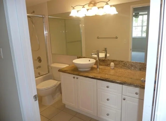 a bathroom with a granite countertop sink toilet and shower