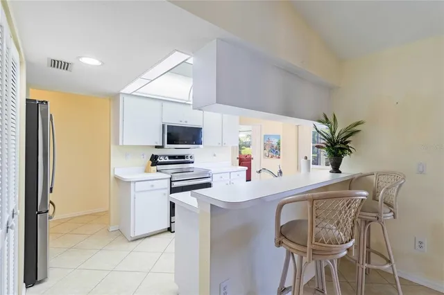 a kitchen with stainless steel appliances a sink a stove a microwave a refrigerator and cabinets