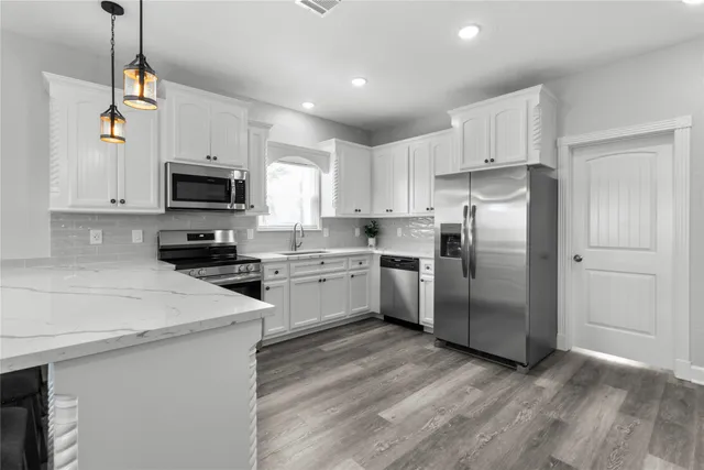 a kitchen with granite countertop a refrigerator a sink a stove a microwave and wooden floor