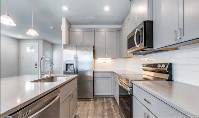 a kitchen with stainless steel appliances granite countertop a sink a stove and a refrigerator