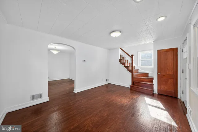 an empty room with wooden floor and stairs