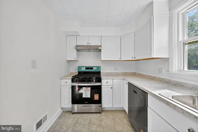 a kitchen with stainless steel appliances granite countertop a stove and a white cabinets