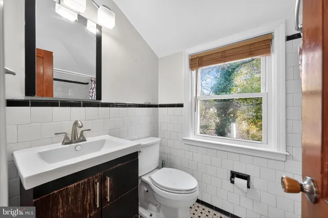 a bathroom with a sink a mirror a toilet and a window